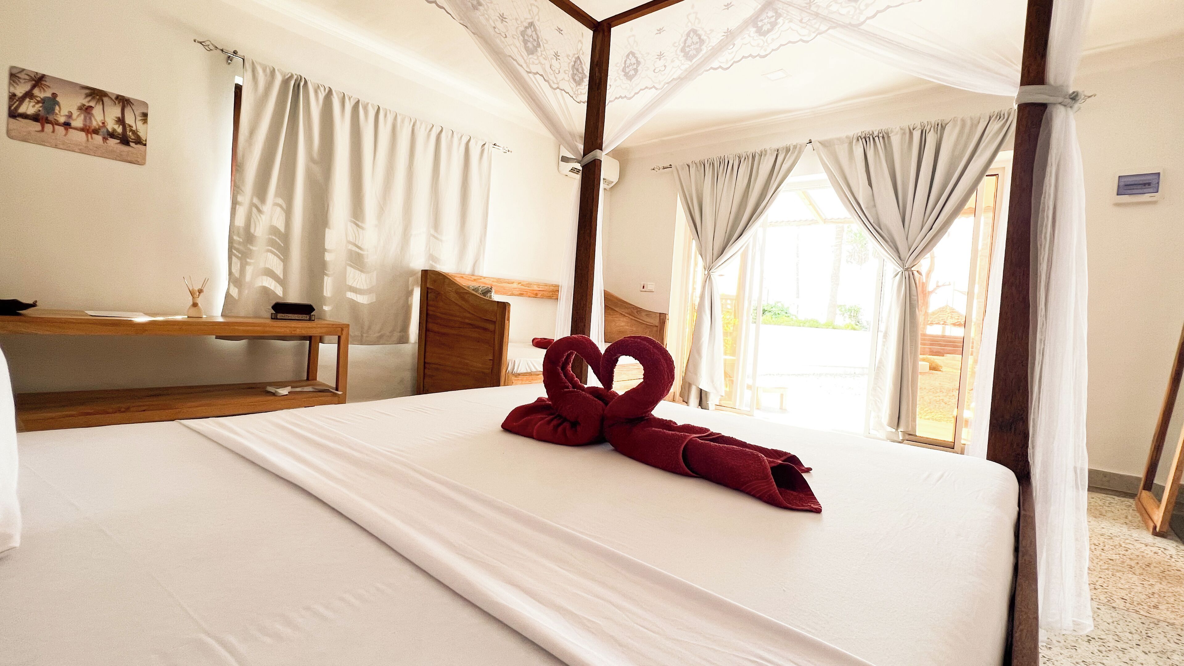 Ein Hotelzimmer mit Bett, Nachttisch aus Holz, Schreibtisch und einem Bild an der Wand.