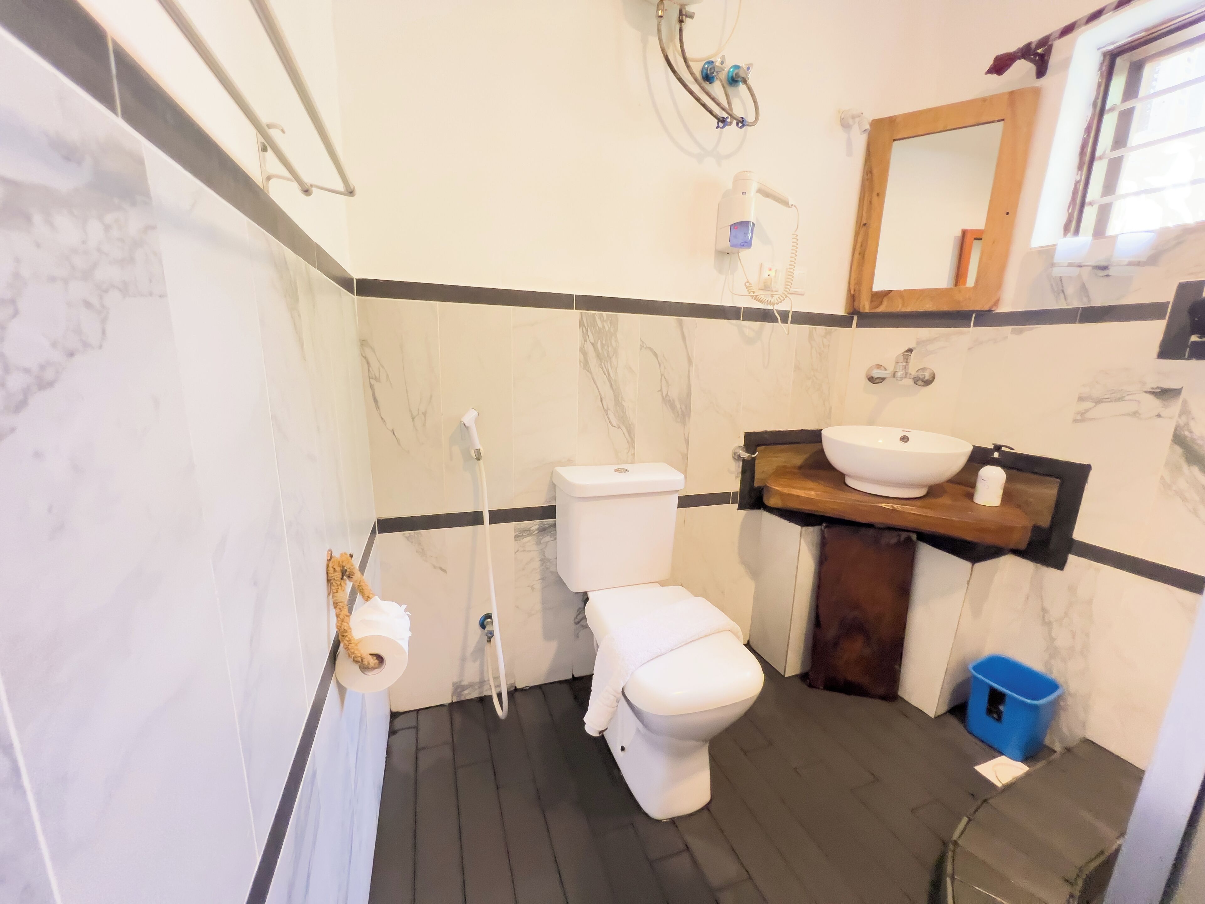 A bathroom with a toilet, a sink, a shower, and a mirror.