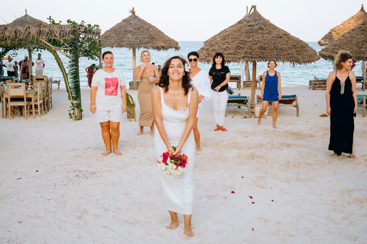 A beach wedding with guests and a bride in a white dress holding a bouquet.