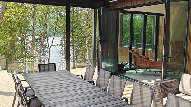 A covered outdoor dining area with a view of a lake and trees.