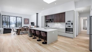 A modern kitchen with a central island, bar stools, and a dining area with a table and chairs.