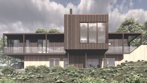 A modern multi-story building with large windows and a flat roof, surrounded by greenery.