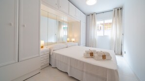 A hotel room with a large bed, a wardrobe, a mirror, and a window with curtains.