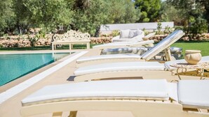 Zona junto a la piscina con tumbonas y un banco de piedra.