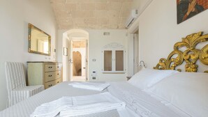 Una habitación de hotel con una cama grande, un aparador, un espejo y una puerta que da a otra habitación.