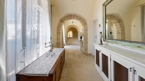 Un pasillo con un banco, un espejo grande y una escalera que lleva a otra habitación.