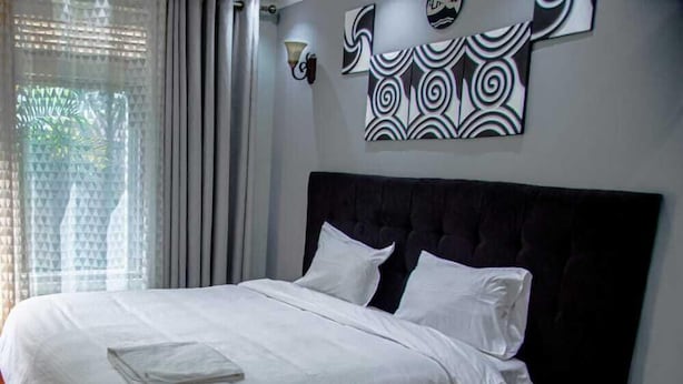 A neatly made bed with white linens in a room with a dark headboard.