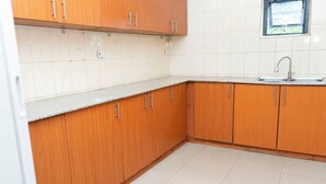A kitchen with wooden cabinets, a white tiled backsplash, and a stainless steel sink.