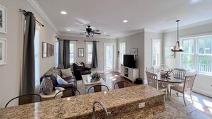 A spacious living room with a sofa, a dining table with chairs, a kitchen area with a granite countertop and sink, and a ceiling fan. - Yellowfin in the Steinhatchee Landing (Steinhatchee)