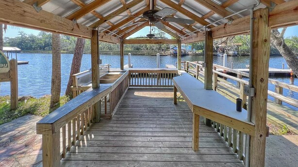 A wooden deck with a metal roof, overlooking a body of water with docks and boats. - Yellowfin in the Steinhatchee Landing (Steinhatchee)