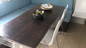 Ett rum med ett matbord, två korgar av rotting, en blå soffa och en hylla med brädspel.