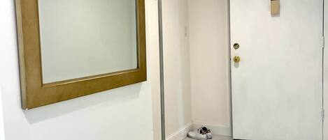 A hallway with a large mirror, a coat rack, and a door with a keycard lock.