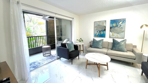 Een moderne woonkamer met een bank, fauteuils, een salontafel en een schuifdeur naar een balkon.