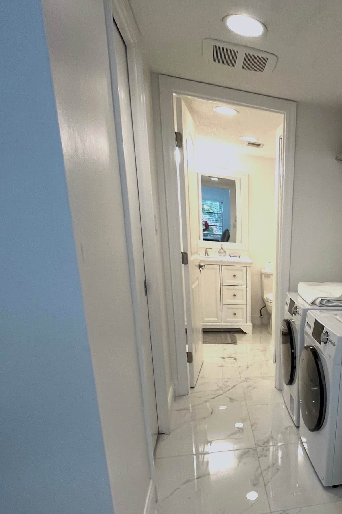 A laundry room with a washing machine and dryer, a white sink with a mirror, and a toilet.