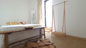 Ein Schlafzimmer mit einem Bett, einem Holztisch, einem gewebten Korb und einem Hängesessel.