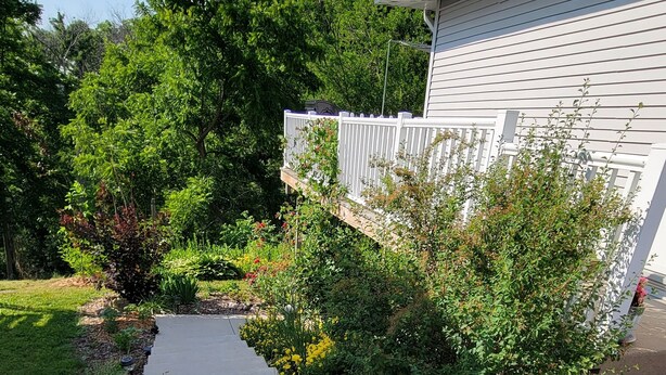A concrete pathway leading to a white house with a white fence and lush greenery. - Private entrance/space. Peaceful getaway. Close to events. King bed. 
Amenities! (Dubuque)
