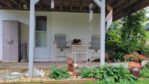 A covered porch with two wicker chairs, a small table, and a potted plant. - Private entrance/space. Peaceful getaway. Close to events. King bed. 
Amenities! (Dubuque)