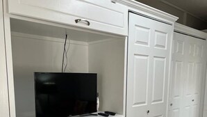 Un armario blanco con varios cajones y un televisor encima.