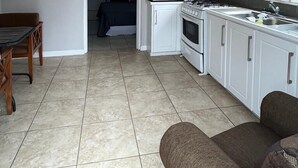 Una cocina compacta con alacenas blancas, un microondas, una estufa y un ventilador de techo.