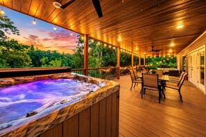 A hot tub on a wooden deck with outdoor furniture and string lights. - Riverfront Retreat | Fish, Kayaking & Hot Tub (Broken Bow)