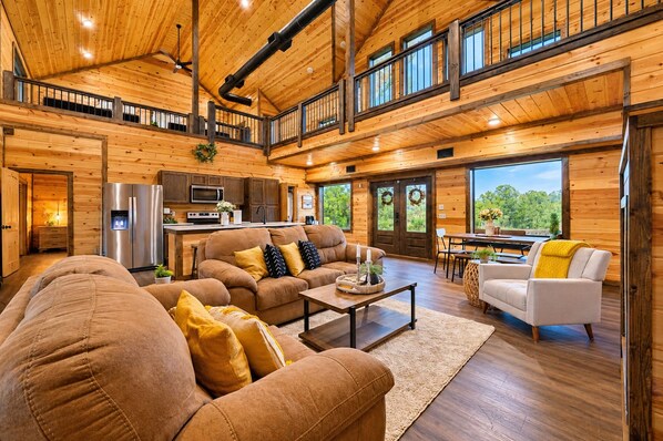 A spacious cabin interior with a kitchen, dining area, and two seating areas.