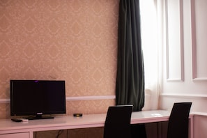 Work in comfort with a desk, flat-screen TV, and digital clock.