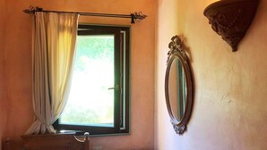 A bedroom with a bed, a bedside table, a mirror, and a window with curtains. - Cala del Faro - Maestrale (Arzachena)