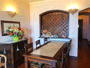Enjoy meals in this beautifully set dining area with a long table, comfortable chairs, and a vase with fresh flowers.