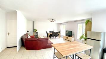 Una cucina moderna con zona pranzo, divano, televisore e frigorifero.