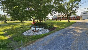 A residential driveway with a gravel path, a swing set, and a small garden area with white pebbles and a planter box. - New Waterfront! Drop Anchor on Brannocks Bay. An Amazing waterfront retreat! (Cambridge)