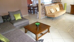 Een woonkamer met een bank, een salontafel en een eethoek op de achtergrond.