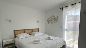 Een slaapkamer met een bed, nachtkastjes, een wandlamp en een raam met uitzicht.