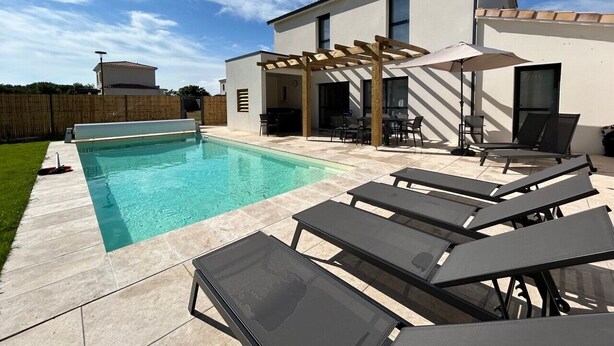 Een modern zwembad met een pergola, lounge fauteuils en een patio tafel.