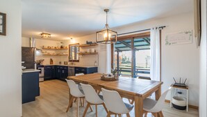 Uma cozinha moderna com uma mesa de jantar de madeira, cadeiras brancas e um lustre.