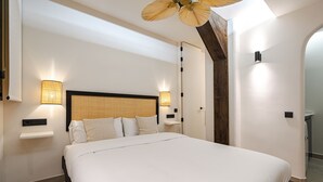Ein modernes Hotelzimmer mit einem großen Bett, zwei Nachttischlampen, einem Deckenventilator und einem kleinen Nachttisch.