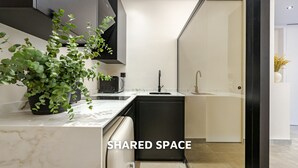 Eine moderne Küche mit einem schwarzen Geschirrspüler, einem Waschbecken und einer Mikrowelle. Auf der Arbeitsfläche steht ein Blumentopf.