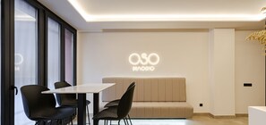 A modern interior with a sofa, chairs, a table, and a wall with 'OSO MADRID' illuminated signage.