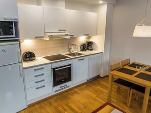 A modern kitchen with white cabinetry, a built-in oven, a microwave, and a coffee maker. - Ruka ski chalets 46, 1207 by Interhome (Haukipudas)