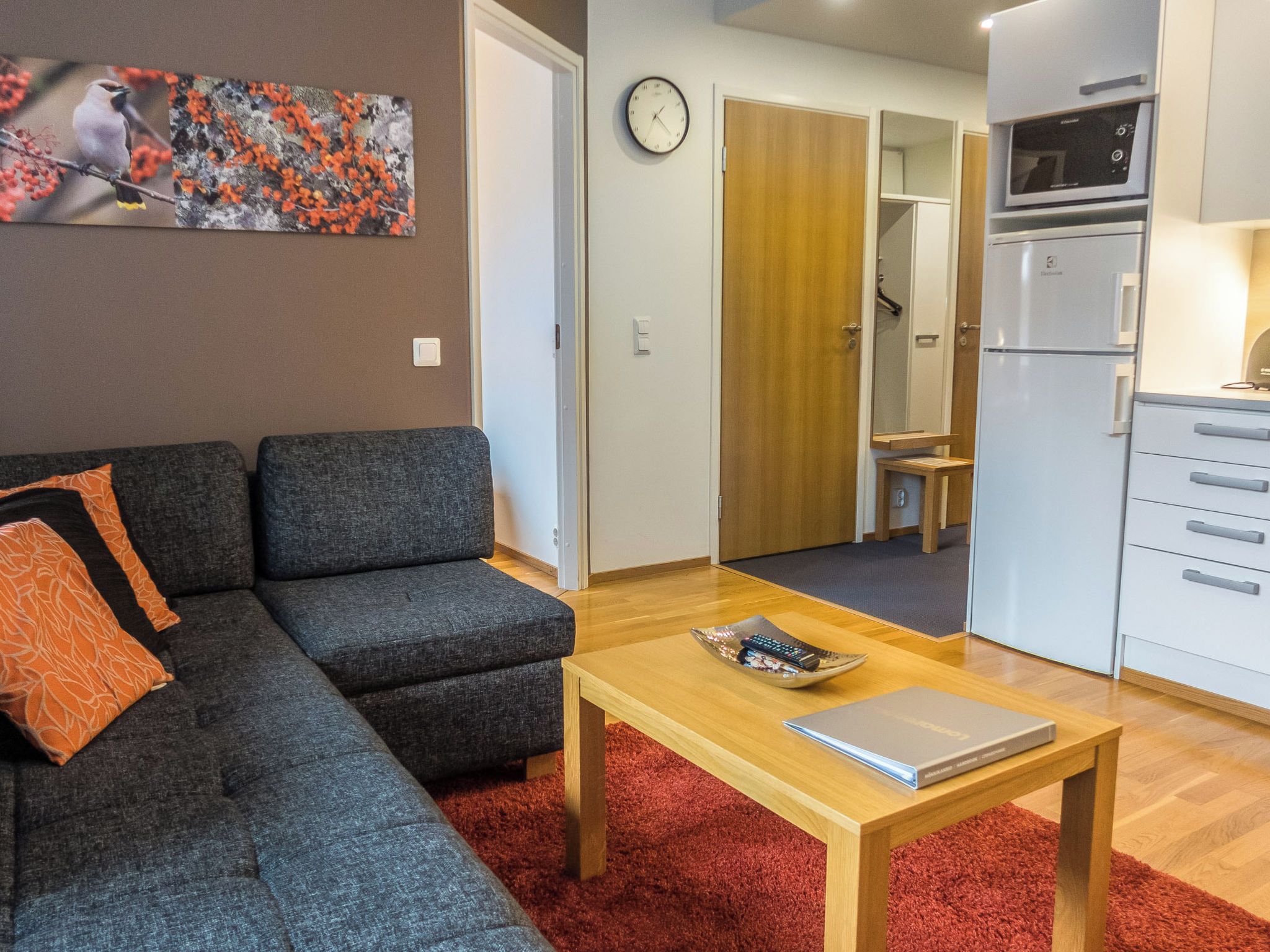 A modern living room with a grey sofa, a wooden coffee table, and a red rug.