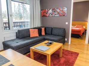 A modern living room with a grey sectional sofa, a wooden coffee table, and a red rug. - Ruka ski chalets 46, 1207 by Interhome (Haukipudas)