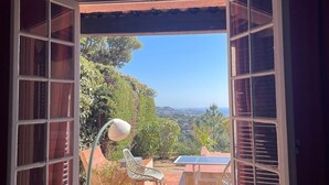 Une terrasse ouverte avec une table et des chaises, une lampe blanche et une vue sur le paysage.