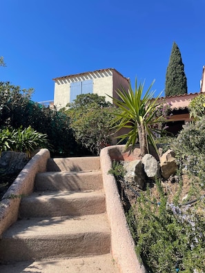A set of stone steps leading up to a building with a tiled roof and a blue shutter.