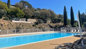 Une piscine avec des chaises longues et un mur de pierre en arrière-plan.