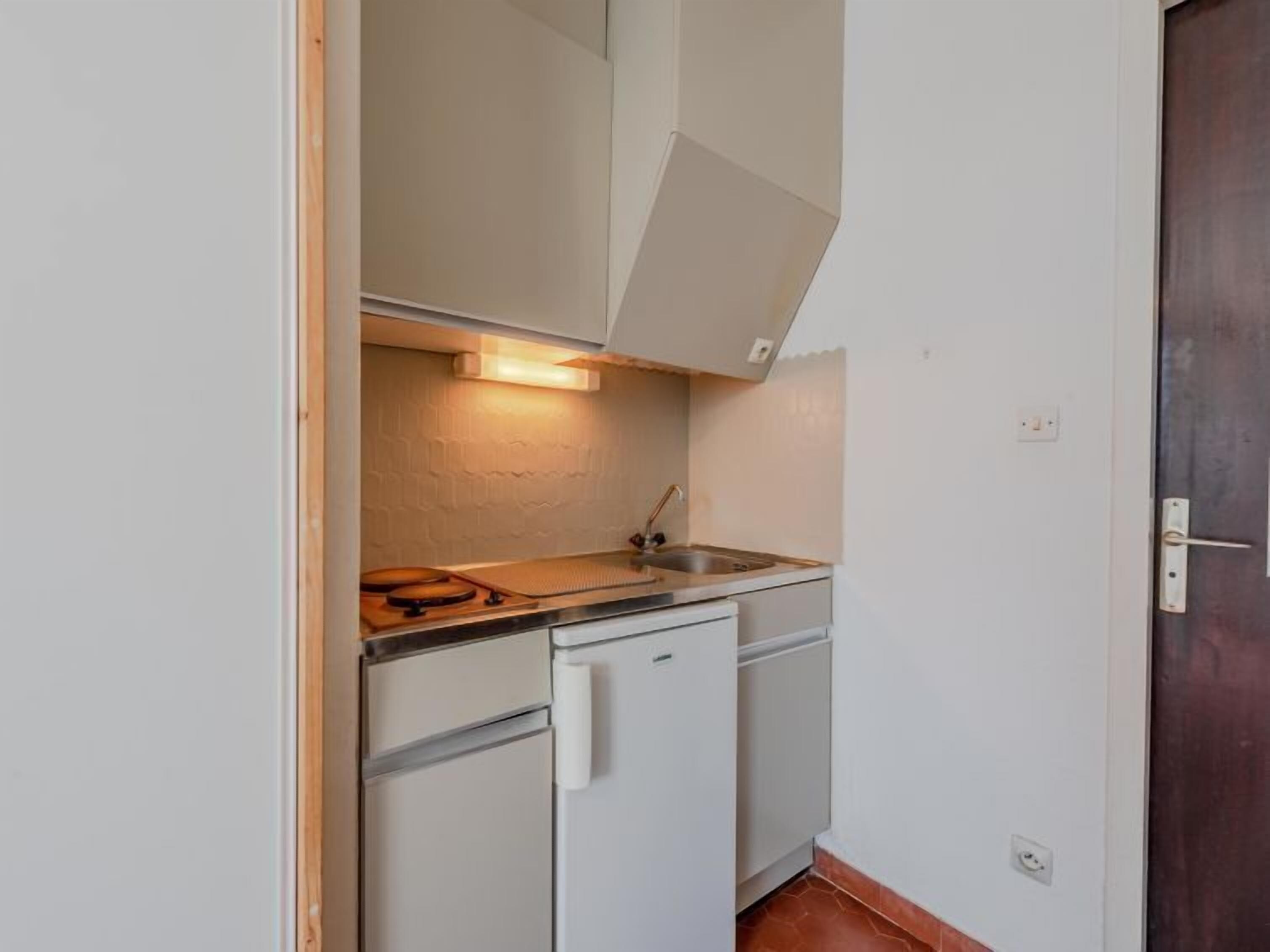 A compact kitchen with a sink, a small refrigerator, and a countertop.