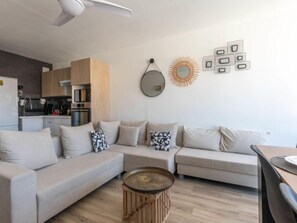A modern living room with a sectional sofa, a coffee table, and a kitchen in the background. - Les Huniers by Interhome (Le Grau du Roi)