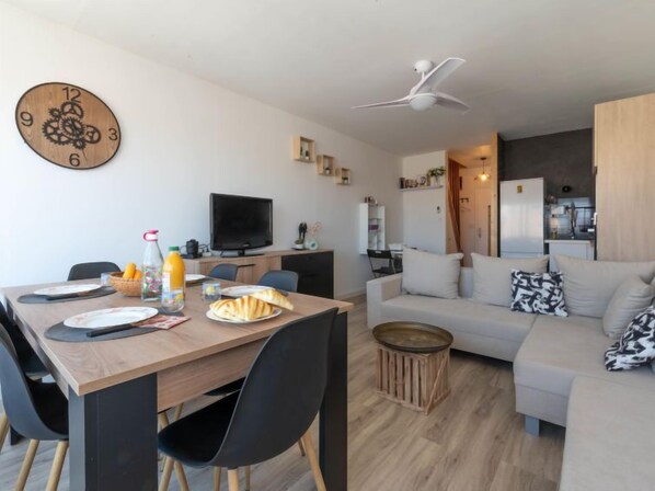 Ein modernes Wohnzimmer mit einem Holzespeisetisch, schwarzen Stühlen, einem weißen Sofa und einem Deckenventilator.