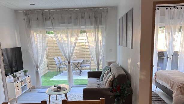 Ein modernes Wohnzimmer mit Sofa, Fernseher und Essbereich.