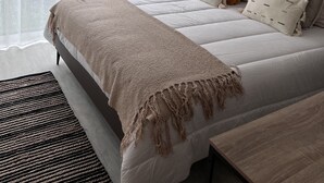 Ein Schlafzimmer mit einem großen Bett, transparenten Vorhängen und Blick ins Freie.