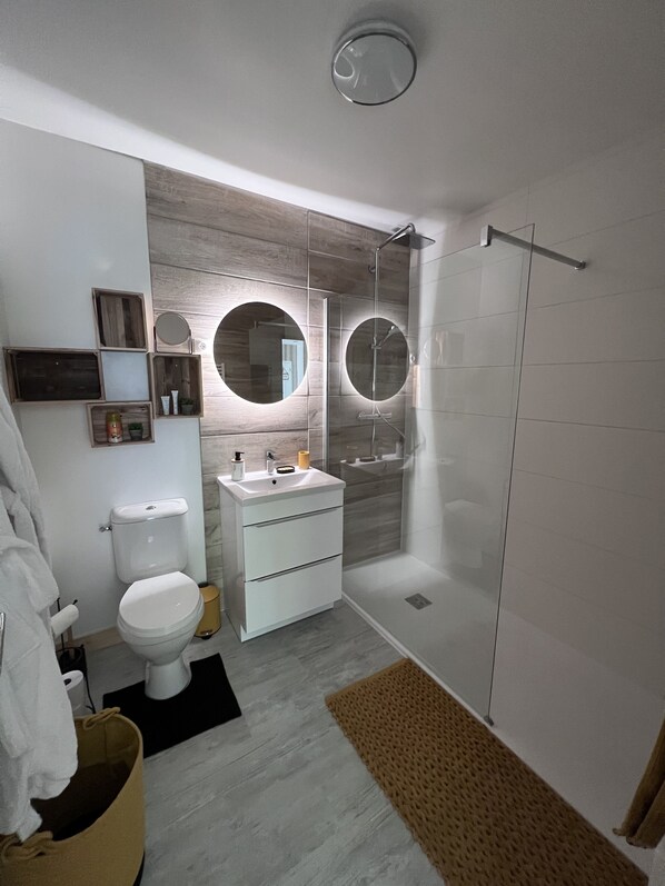 A modern bathroom with a toilet, sink, and shower.