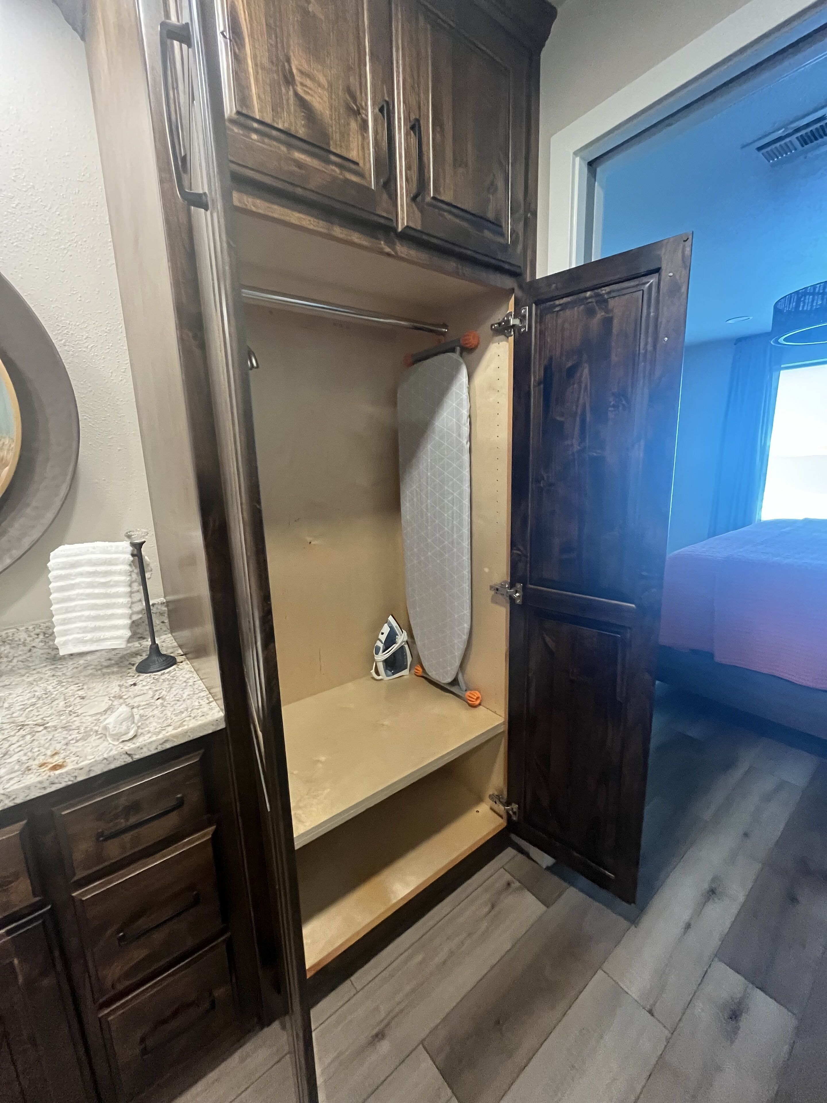Ein Zimmer mit einem Holzschrank, einer kleinen Ablage und einer Tür zu einem weiteren Raum.